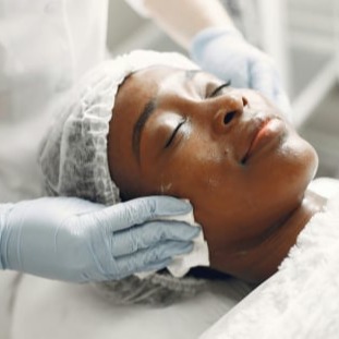 Closeup of a woman laying down, relaxing, receiving a facial, links to Facial Services for Athena's Glow